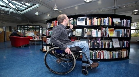 a man in a wheel chair sitting in front of bookshelves