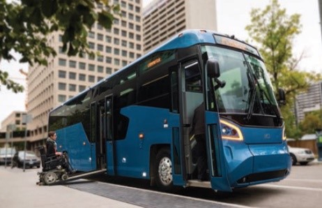 A person in a wheelchair boarding a bus that is parked on the side of a street in the city